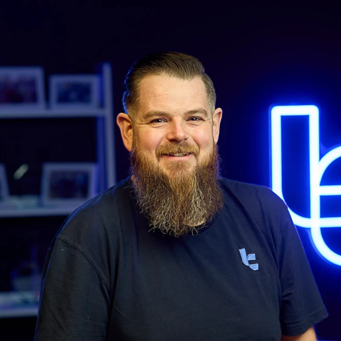 A man with a full beard and short brown hair wearing a navy shirt.