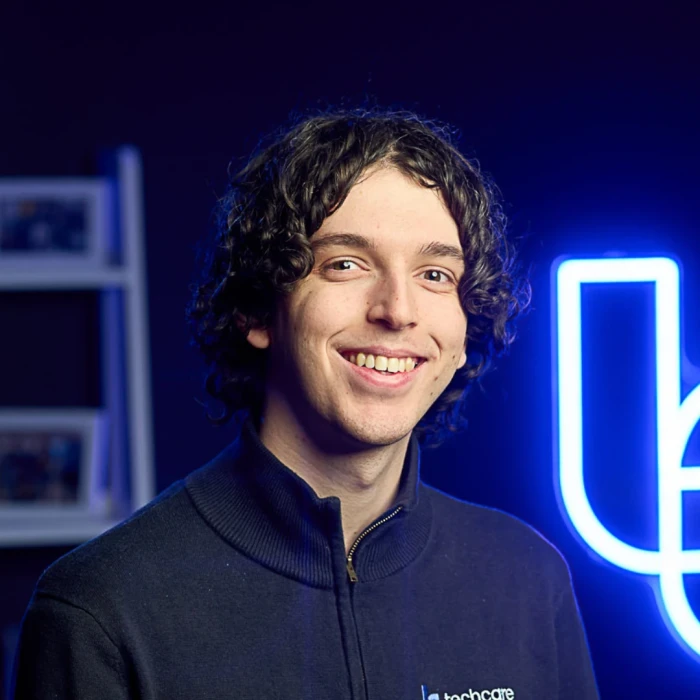 A young man with dark curly hair, wearing a navy shirt.