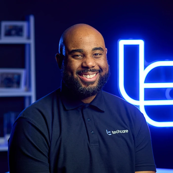 A man with a shaven head, short beard, and a cheeky smile.